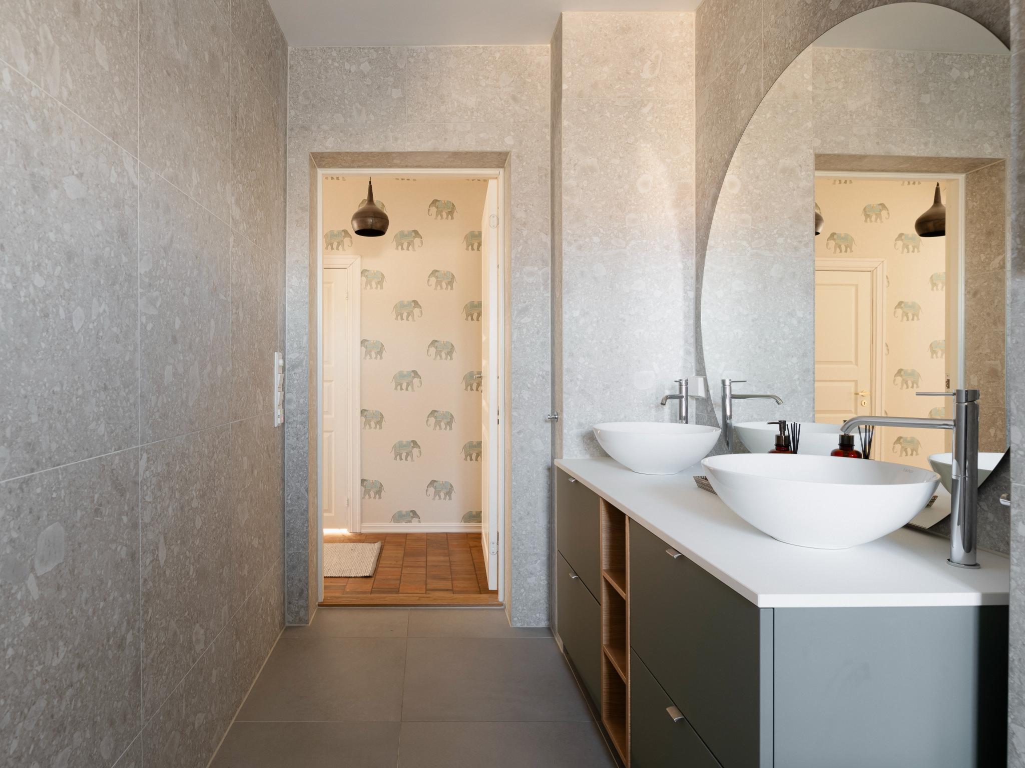 Badet fremstår eksklusivt med store fliser, smale fuger og en moderne innredning.